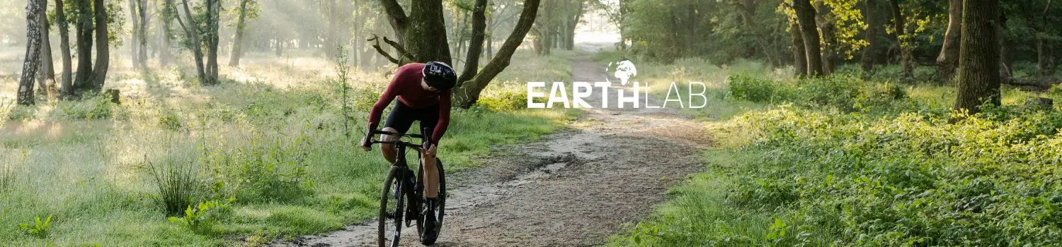 A cyclist in a red jersey rides through a forest path with the EarthLab logo visible.