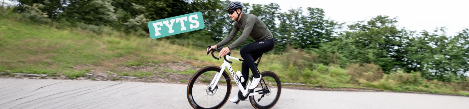 A cyclist wearing a helmet rides a white Canyon road bike on a paved path.