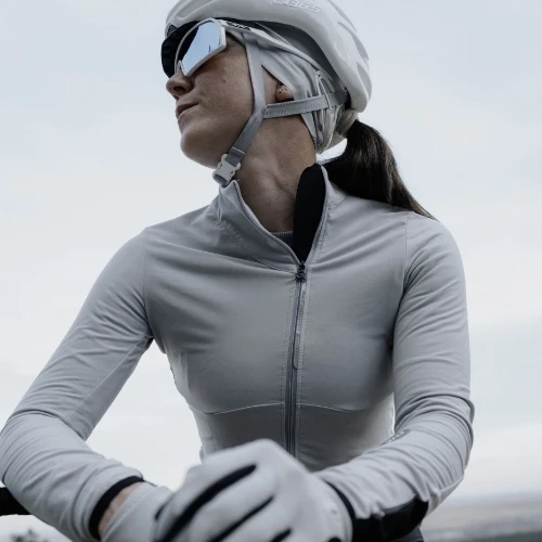 A female cyclist wearing grey cycling gear and a helmet, looking to the side.