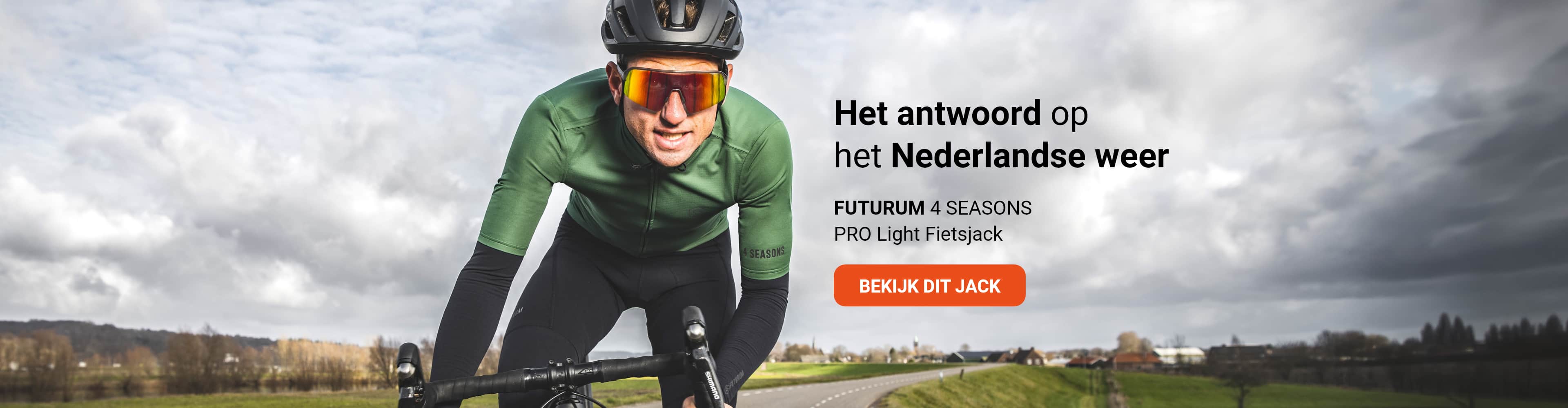 A cyclist wearing a green Futurum 4 Seasons Pro Light cycling jacket rides on a road. The background shows a cloudy sky and open fields.