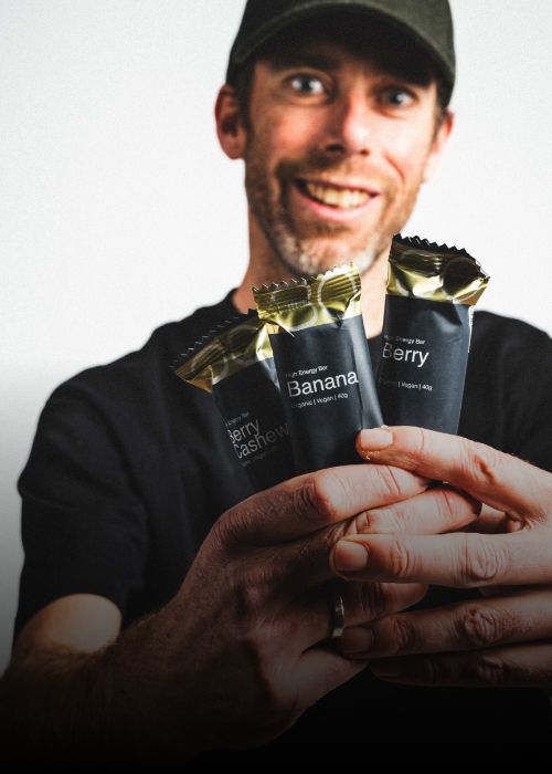 Laurens ten Dam holding three energy bars labeled Berry, Banana, and Berry Cashew.