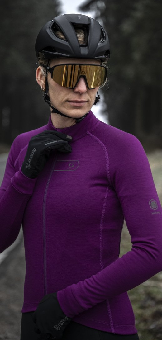A cyclist wearing a purple jersey, black helmet, and reflective sunglasses in an outdoor setting.
